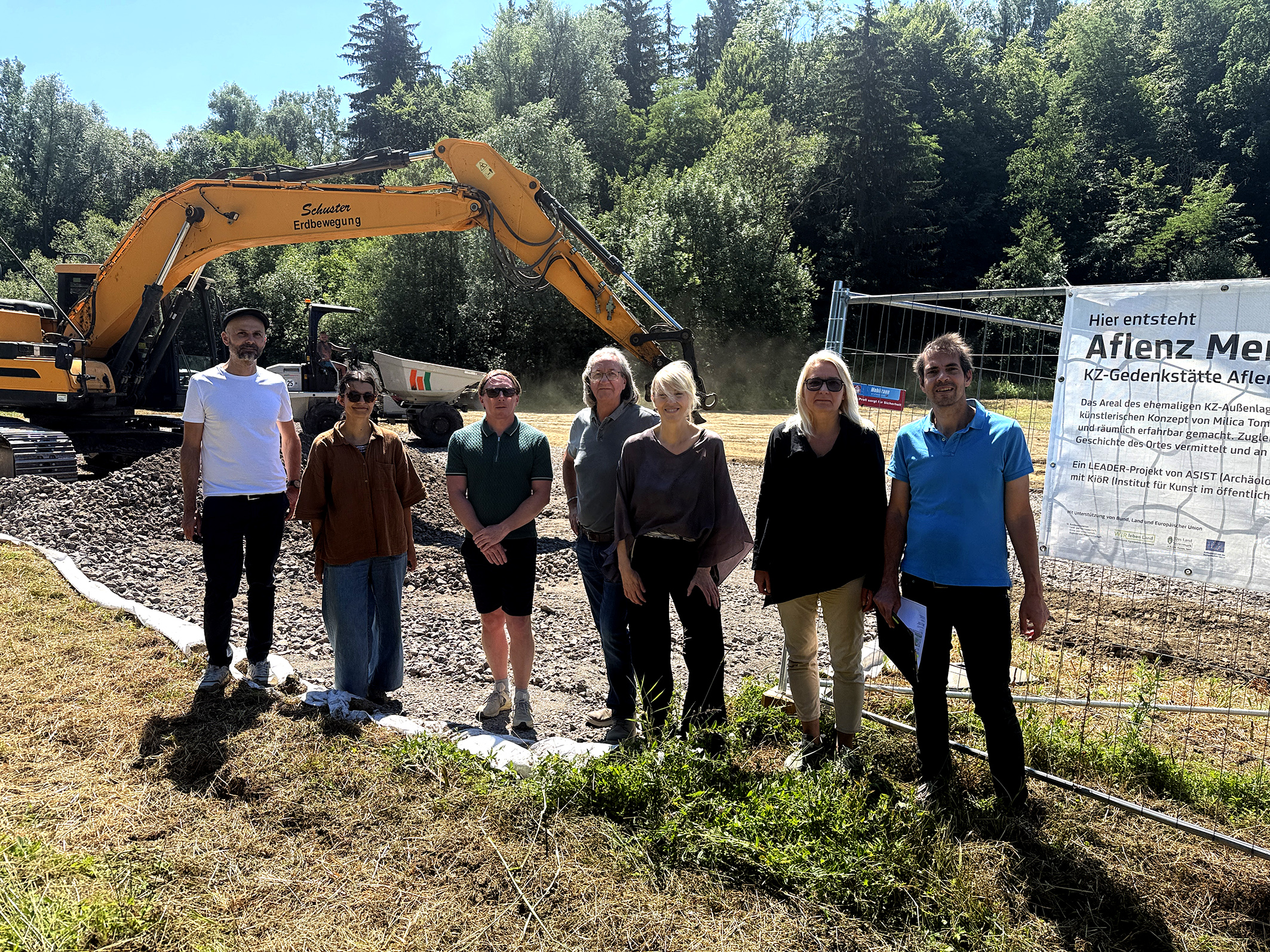 KZ-Gedenkstätte Aflenz: Gruppe vor Baustelle mit Bagger und Hinweistafel